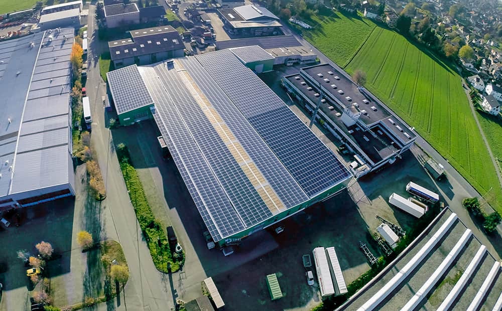 Vue aérienne des bâtiments de production de Woodwork AG Huttwil avec une immense couverture photovoltaïque